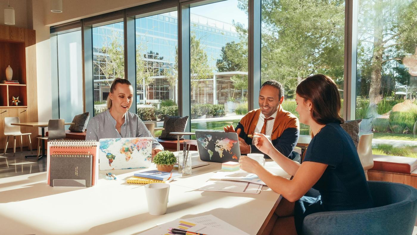 A recruitment team collaborating over laptops in a bright office